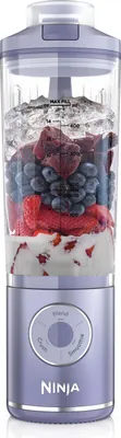 A purple and clear Ninja blender filled with ice, berries, and yogurt, set against a white background.