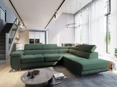 A modern living room with a large green sectional sofa, a coffee table, and a staircase.