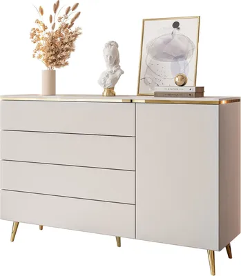 A white dresser with gold accents and legs, decorated with a bust, a vase of dried flowers, and a framed picture.
