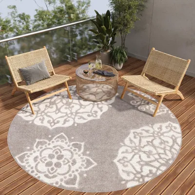 A round rug with a mandala pattern on a wooden deck with two chairs and a coffee table.