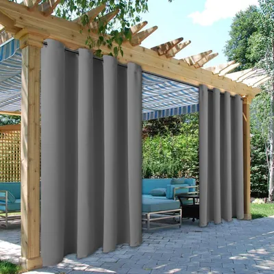 Outdoor patio area with a wooden pergola covered by striped awnings and draped with gray outdoor curtains.