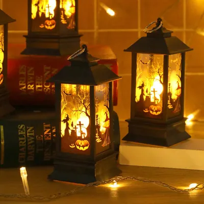 Several Halloween-themed LED lanterns are displayed on a surface, with string lights in the foreground.