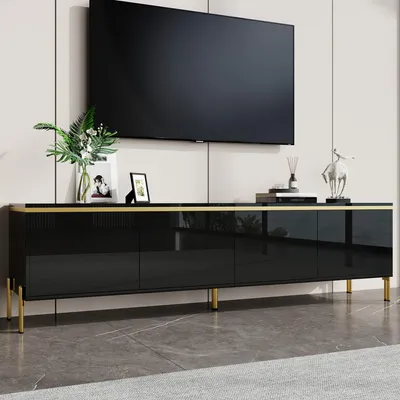 A black TV cabinet with gold accents and legs, with a TV mounted above it.