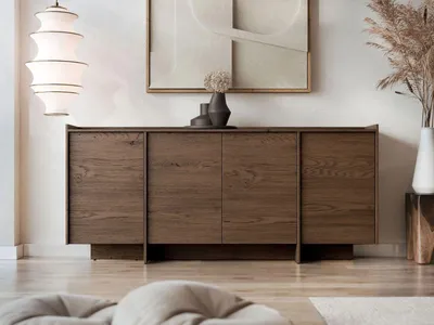 A wooden sideboard with four doors is displayed in a well-lit, modern living room setting, adorned with decorative vases and dried flowers.