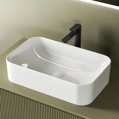 A white ceramic sink with a black faucet sits on a green vanity.