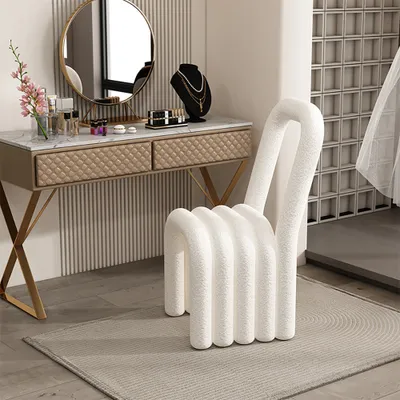 A stylish vanity area with a makeup table and a unique chair.