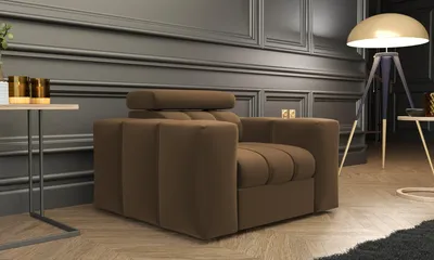 A brown armchair is placed in a living room with dark gray paneled walls and a wooden floor. A floor lamp and a side table are also visible.