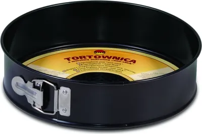 A black springform cake pan with a removable bottom and a silver latch is shown against a white background. A yellow and orange label with text is visible inside the pan.