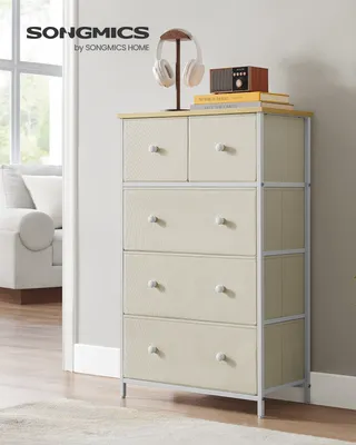 A SONGMICS chest of drawers with fabric drawers is displayed in a room setting, with a sofa and window in the background.