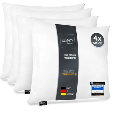 A stack of four white pillows, with a product label on the front pillow.
