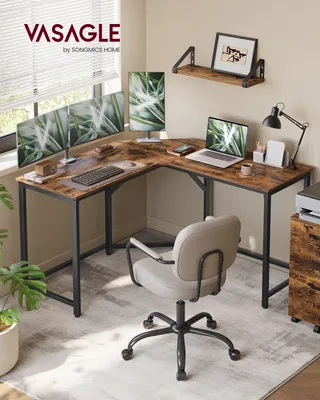 A home office setup with an L-shaped desk, multiple monitors, a laptop, and a chair.