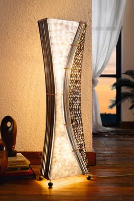 A tall, decorative floor lamp is shown in a room with a window and curtains in the background.