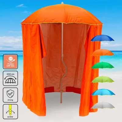 An orange beach umbrella with side panels set up on a beach with the ocean and sky in the background. Several smaller umbrellas in different colors are displayed to the right.