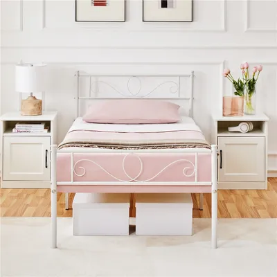 A white metal bed frame with a pink mattress and pillow, placed in a bedroom setting with nightstands on either side.