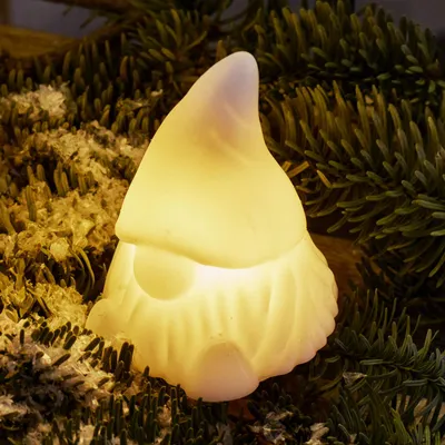 A glowing gnome figurine nestled amongst pine needles and moss.