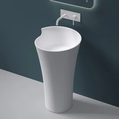 A modern white freestanding sink with a wall-mounted faucet against a dark teal wall.