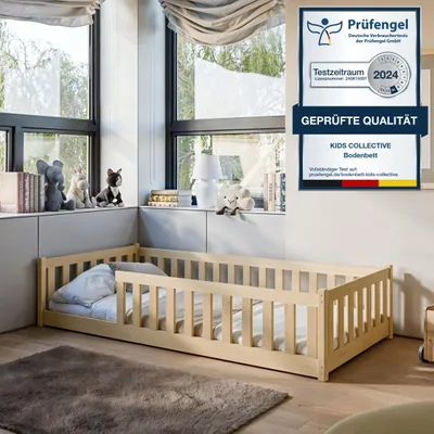 A wooden children's bed with safety rails is placed in a room with large windows and decorative items on a shelf.