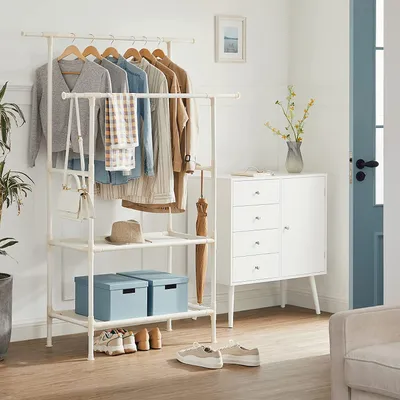 A well-organized entryway or dressing area featuring a clothing rack with various garments and accessories, a white cabinet, and a chair.