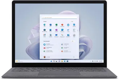 A Microsoft Surface Laptop 5 is shown open, displaying the Windows 11 Pro operating system interface on its screen.