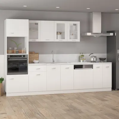 A modern white kitchen with various cabinets, an oven, a sink, and a refrigerator.