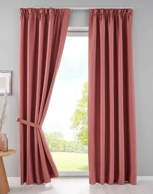 Two pink curtains are shown hanging in front of a window, with one curtain tied back with a fabric band.