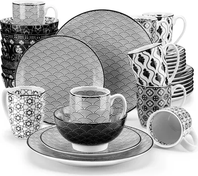 A collection of black and white patterned ceramic dishes and mugs are arranged on a white background.