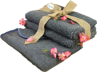 A stack of folded gray blankets tied with a burlap ribbon and decorated with pink flowers.