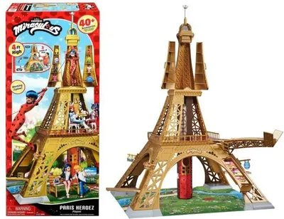 A product box and the toy playset it contains, depicting a golden Eiffel Tower playset with characters from Miraculous Ladybug.