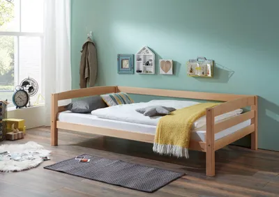 A bedroom scene with a wooden daybed, bedding, and decorative items on the wall.