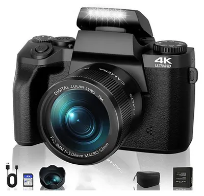 A black digital camera with accessories displayed in front of it.
