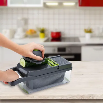 A person is using a vegetable slicer in a kitchen.