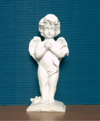 A white angel figurine is standing on a book against a blue textured background.