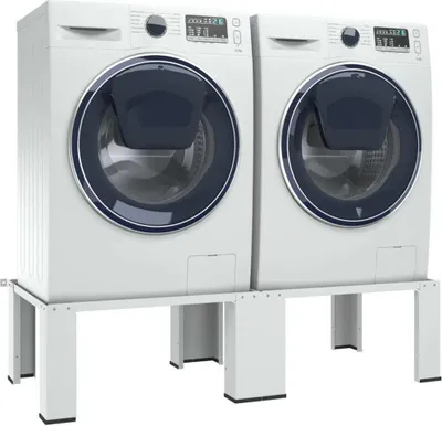Two white washing machines are placed side-by-side on a white stand.