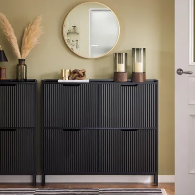 A hallway or living room setting with a shoe cabinet, mirror, and decorative items.