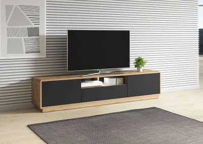 A modern living room scene featuring a TV stand with a television on top, a rug on the floor, and artwork on the wall.