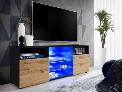 A modern TV stand with a black matte body, wotan matte front, and illuminated blue shelves, displaying a TV and decorative items.