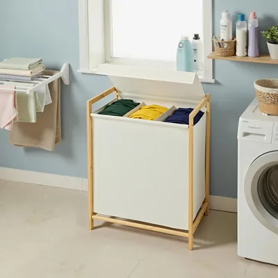 A laundry room with a washing machine, drying rack, and a multi-compartment laundry hamper.