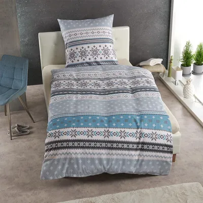 A bed with blue and gray snowflake patterned bedding and a pillow.