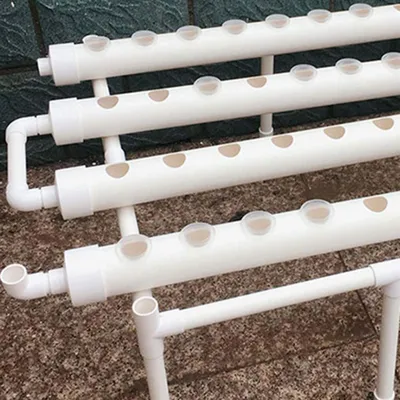A close-up view of a hydroponic system with white pipes and circular openings.