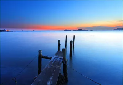 Produktbild von Wallario Fototapete Vliestapete, seidenmatte Oberfläche, einfache Verarbeitung, Größe 200 x 140 cm, Motiv Steg im Wasser - Abendstimmung am Meer
