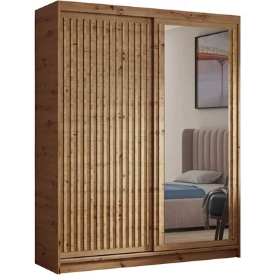 A wooden wardrobe with sliding doors, one of which is a mirror reflecting a bedroom scene.