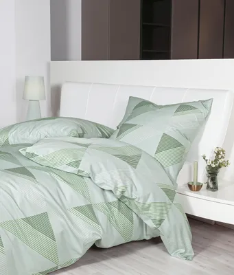 A neatly made bed with green geometric patterned bedding and a white headboard.