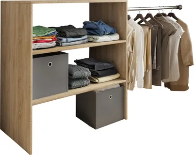 A wooden open wardrobe with shelves and a hanging rail, displaying folded clothes and hanging garments.