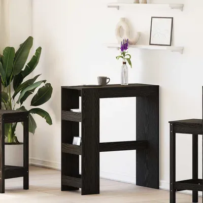 A dark wood bar table with shelves and a small plant in a vase on top, set against a white wall.