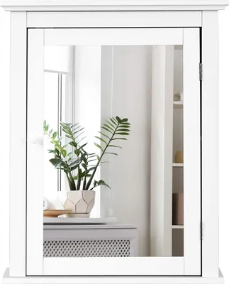 A white bathroom cabinet with a mirror is shown against a white background. A plant in a geometric pot sits on a shelf inside the cabinet, reflected in the mirror.