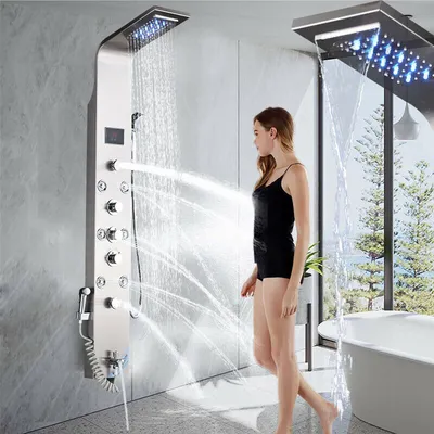 A woman is standing in a modern bathroom, using a multi-function shower panel with LED lights and multiple water outlets.