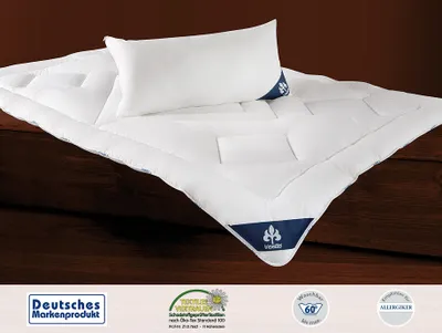 A white duvet and pillow are displayed on a wooden surface.