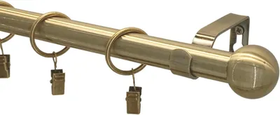 Close-up of a brass curtain rod with rings and clips.