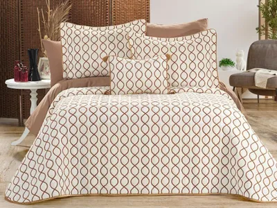 A neatly made bed with a cream and gold patterned duvet set, pillows, and a throw blanket.
