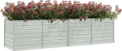 A long, silver metal planter box filled with dense, colorful flowers.